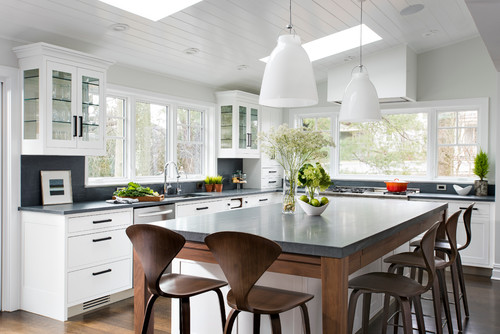 Bright kitchen with white cabinets and dark artificial stone countertops on large island with wooden bar stools