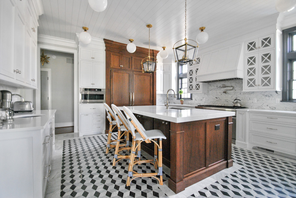 Klassisk inredning av ett avskilt, stort vit vitt u-kök, med en undermonterad diskho, luckor med profilerade fronter, vita skåp, bänkskiva i kvarts, vitt stänkskydd, stänkskydd i marmor, rostfria vitvaror, marmorgolv, en köksö och grått golv