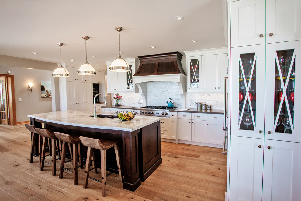 Eat-in kitchen - large coastal l-shaped light wood floor eat-in kitchen idea in Toronto with an undermount sink, shaker cabinets, white cabinets, quartz countertops, white backsplash, stainless steel appliances and an island