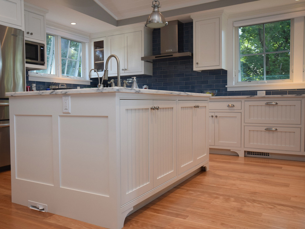 Inspiration for a large cottage u-shaped light wood floor eat-in kitchen remodel in Burlington with a farmhouse sink, beaded inset cabinets, white cabinets, marble countertops, blue backsplash, glass tile backsplash, stainless steel appliances and an island