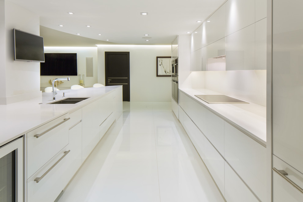 Foto på ett mellanstort funkis kök, med en dubbel diskho, släta luckor, vita skåp, bänkskiva i kvarts, vitt stänkskydd, integrerade vitvaror, marmorgolv, en halv köksö och vitt golv