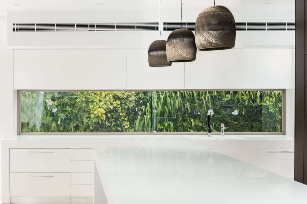 Kitchen - tropical kitchen idea in Sunshine Coast with flat-panel cabinets, white cabinets, glass sheet backsplash and an island