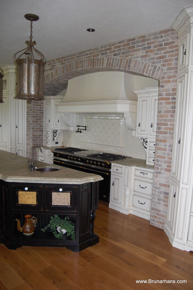 Cette photo montre une très grande arrière-cuisine parallèle chic en bois vieilli avec un placard à porte affleurante, un plan de travail en granite, un sol en bois brun et îlot.