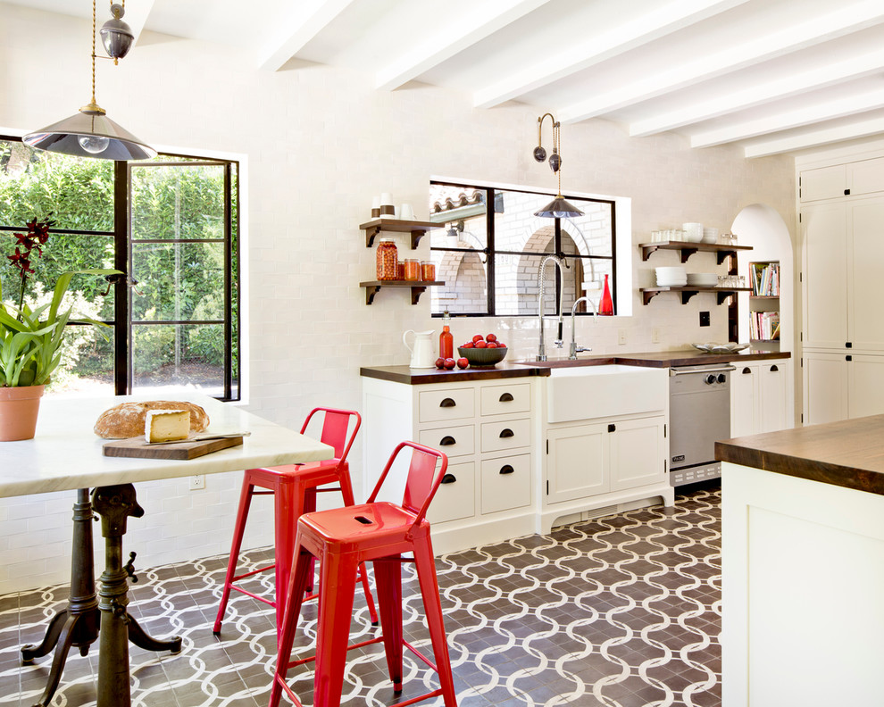 Example of a tuscan eat-in kitchen design in Portland with a farmhouse sink, shaker cabinets, white cabinets, wood countertops, white backsplash, subway tile backsplash and stainless steel appliances
