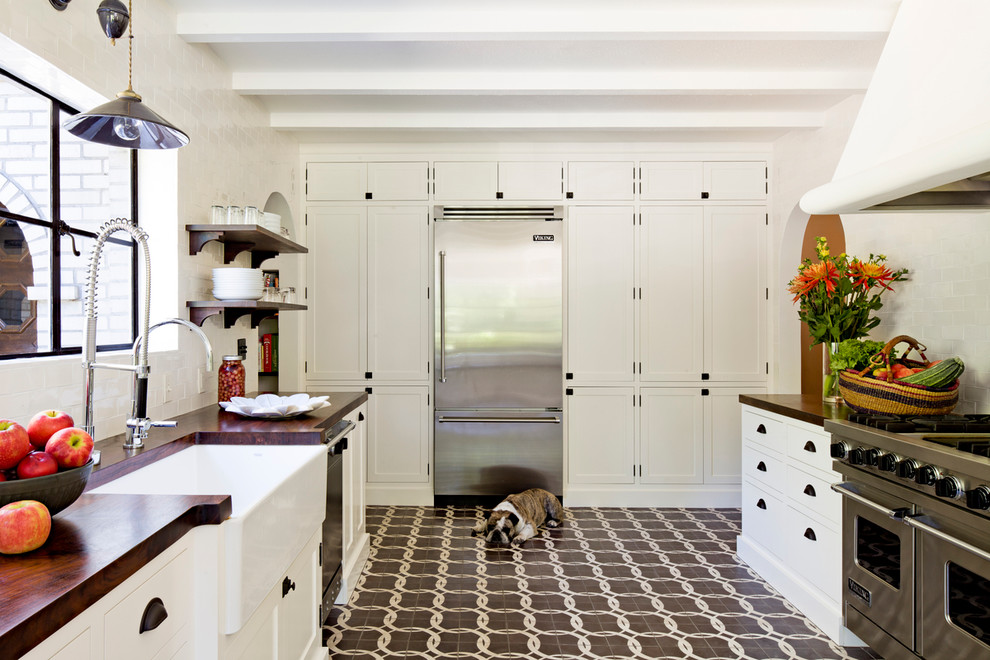 Idéer för att renovera ett avskilt medelhavsstil kök, med en rustik diskho, skåp i shakerstil, vita skåp, träbänkskiva, vitt stänkskydd, stänkskydd i tunnelbanekakel och rostfria vitvaror