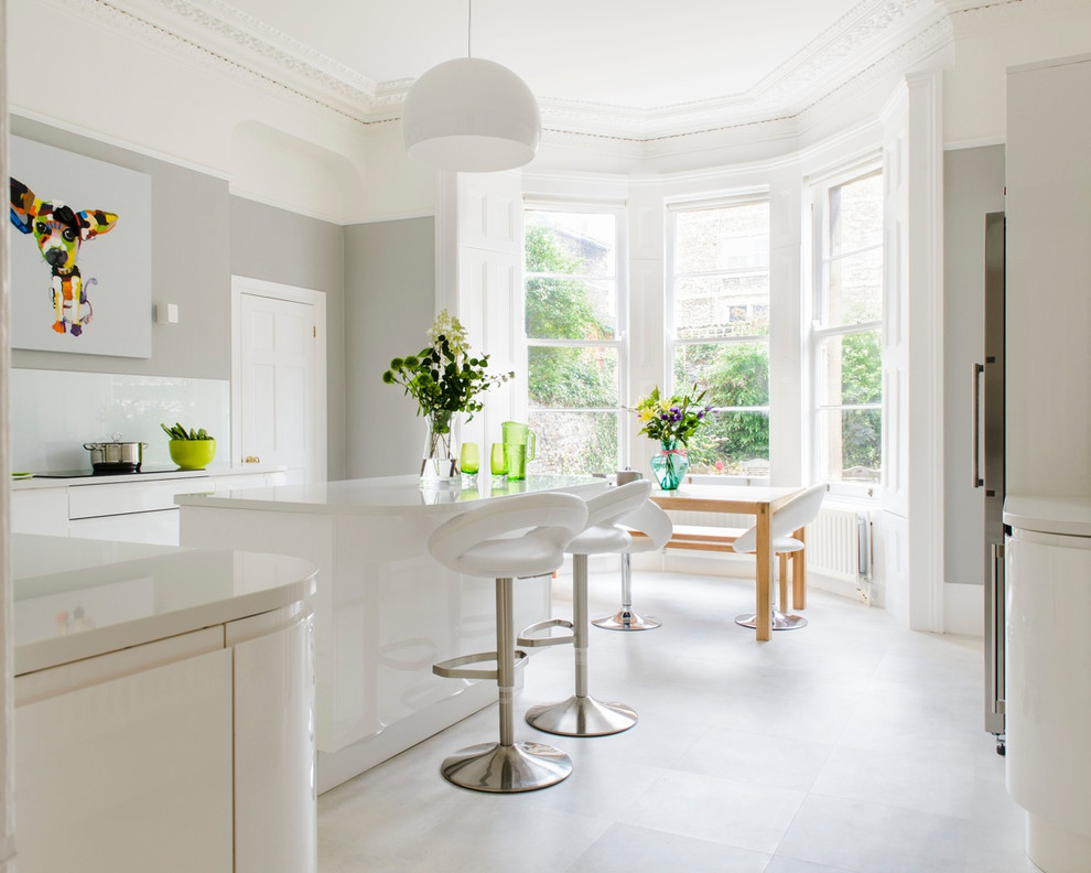Moderne Wohnküche mit flächenbündigen Schrankfronten, weißen Schränken, Küchenrückwand in Weiß und Kücheninsel in Sonstige