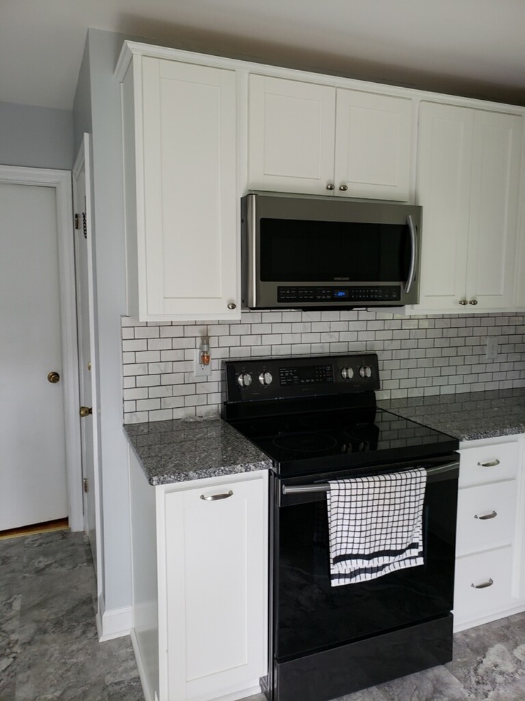 Inredning av ett rustikt avskilt, litet flerfärgad flerfärgat u-kök, med en undermonterad diskho, skåp i shakerstil, vita skåp, granitbänkskiva, vitt stänkskydd, stänkskydd i tunnelbanekakel, svarta vitvaror, vinylgolv och grått golv