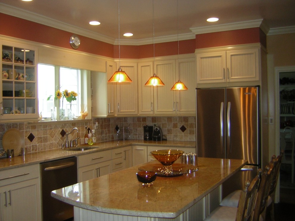 Transitional l-shaped eat-in kitchen photo in New York with an undermount sink, recessed-panel cabinets, white cabinets, granite countertops, brown backsplash, terra-cotta backsplash, stainless steel appliances and an island