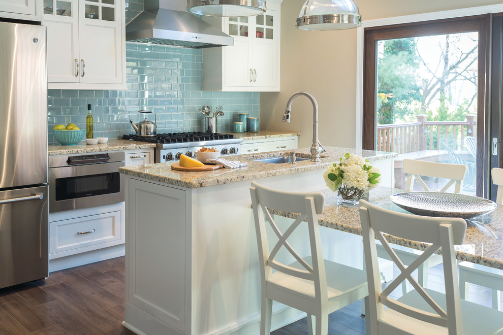 Exempel på ett stort klassiskt linjärt kök med öppen planlösning, med en undermonterad diskho, luckor med profilerade fronter, vita skåp, granitbänkskiva, blått stänkskydd, stänkskydd i glaskakel, rostfria vitvaror, klinkergolv i porslin och en köksö