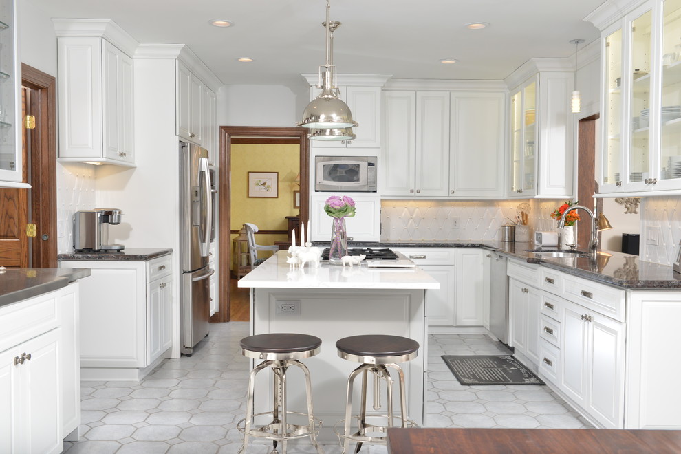 Elegant u-shaped eat-in kitchen photo in Cleveland with an undermount sink, raised-panel cabinets, white cabinets, white backsplash, stainless steel appliances and an island