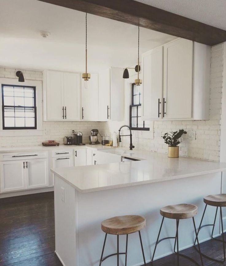 Mid-sized farmhouse l-shaped dark wood floor and brown floor eat-in kitchen photo in Columbus with a farmhouse sink, recessed-panel cabinets, white cabinets, quartz countertops, white backsplash, brick backsplash, stainless steel appliances, a peninsula and white countertops