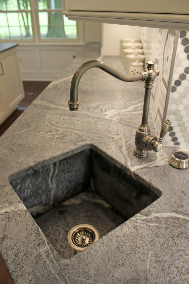 This is an example of a large traditional galley kitchen/diner in Cleveland with a submerged sink, raised-panel cabinets, white cabinets, soapstone worktops, grey splashback, stainless steel appliances, medium hardwood flooring and an island.