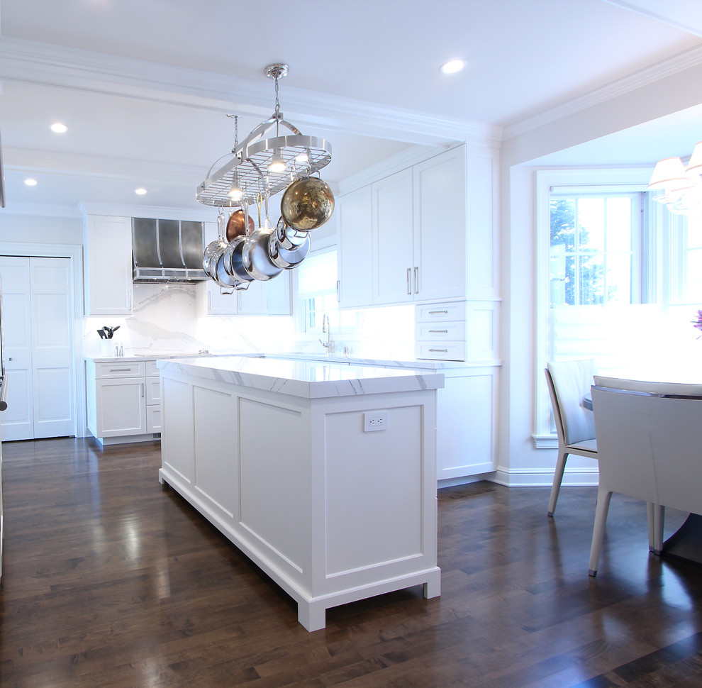 Exempel på ett litet klassiskt vit vitt kök, med en undermonterad diskho, luckor med infälld panel, vita skåp, bänkskiva i kvarts, vitt stänkskydd, stänkskydd i sten, integrerade vitvaror, mörkt trägolv, en köksö och brunt golv