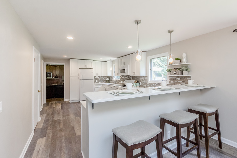 Eat-in kitchen - mid-sized modern l-shaped vinyl floor and beige floor eat-in kitchen idea in New York with a single-bowl sink, shaker cabinets, white cabinets, quartz countertops, beige backsplash, mosaic tile backsplash, white appliances, a peninsula and white countertops