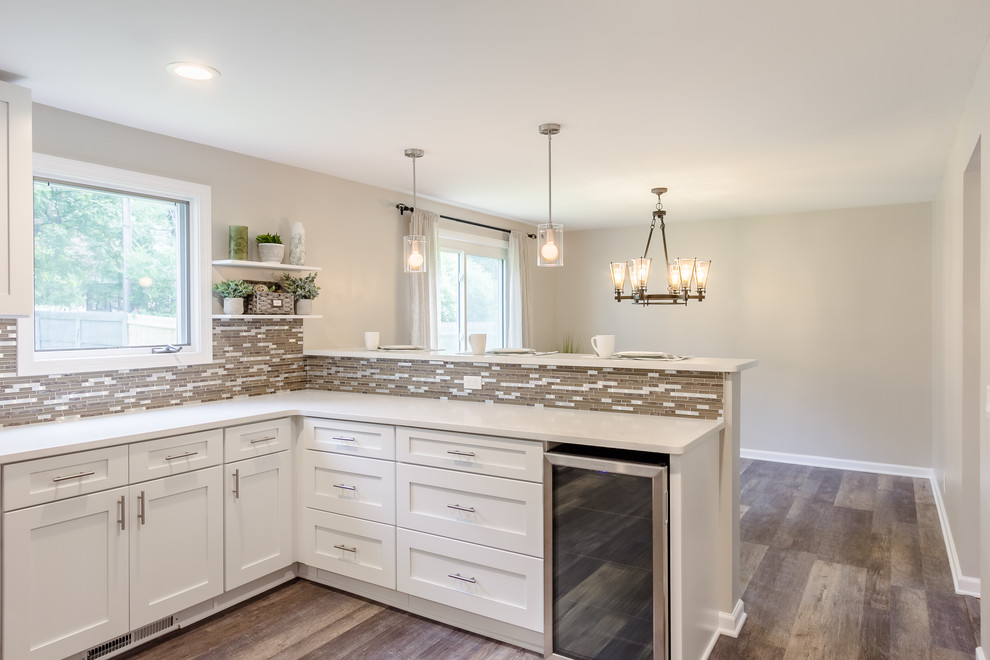 Mid-sized minimalist l-shaped vinyl floor and beige floor eat-in kitchen photo in New York with a single-bowl sink, shaker cabinets, white cabinets, quartz countertops, beige backsplash, mosaic tile backsplash, white appliances, a peninsula and white countertops