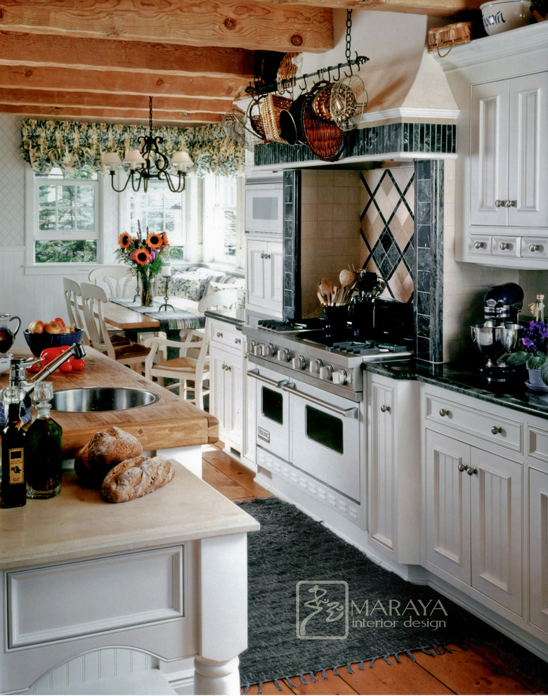 Inredning av ett klassiskt stort kök, med en rustik diskho, luckor med infälld panel, vita skåp, granitbänkskiva, grönt stänkskydd, stänkskydd i stenkakel, vita vitvaror, ljust trägolv och en köksö