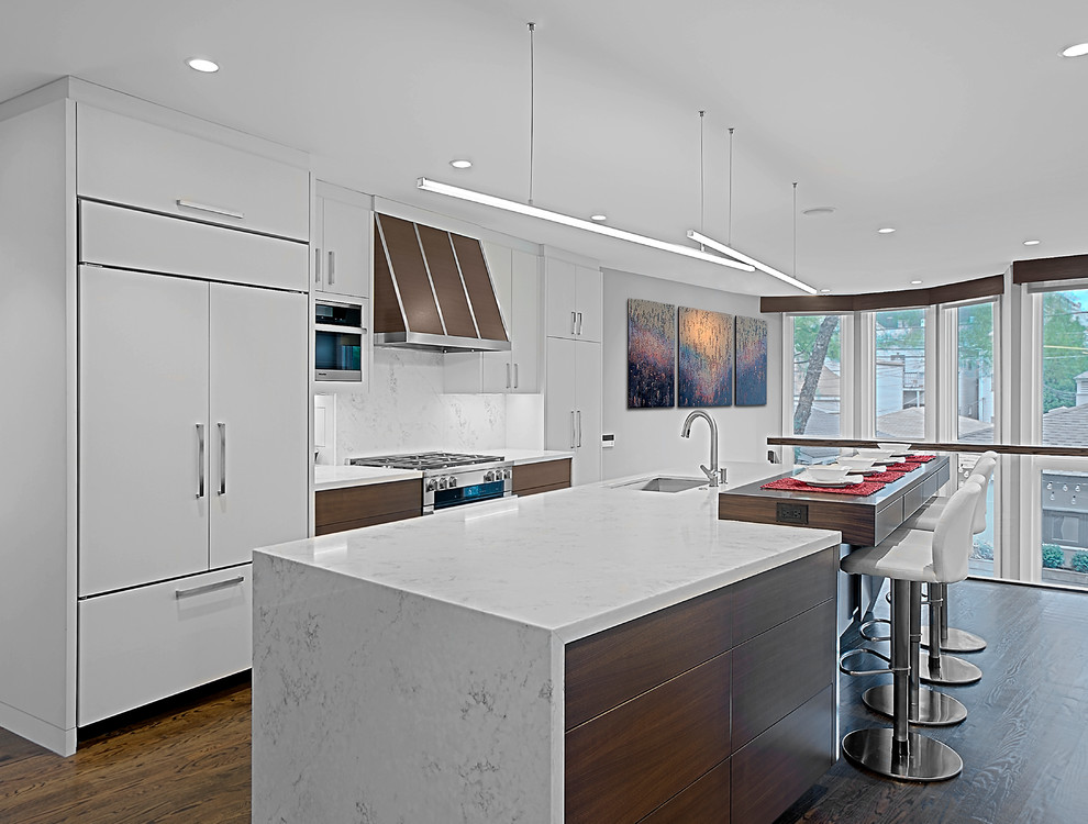 Design ideas for a large contemporary single-wall kitchen in Chicago with a submerged sink, flat-panel cabinets, dark wood cabinets, marble worktops, white splashback, stone slab splashback, stainless steel appliances, dark hardwood flooring, an island, brown floors and white worktops.