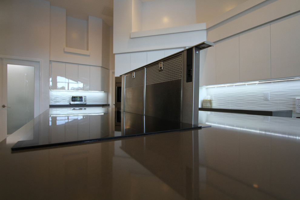 This is an example of a large contemporary u-shaped kitchen/diner in Orlando with a submerged sink, flat-panel cabinets, white cabinets, white splashback, porcelain splashback, stainless steel appliances, porcelain flooring, an island and engineered stone countertops.