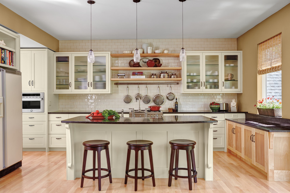 Country u-shaped dark wood floor and beige floor kitchen photo in Chicago with a farmhouse sink, glass-front cabinets, beige cabinets, white backsplash, subway tile backsplash and an island