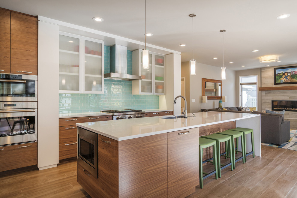 Inspiration for a contemporary galley brown floor kitchen remodel in Chicago with an undermount sink, flat-panel cabinets, dark wood cabinets, blue backsplash, glass tile backsplash, stainless steel appliances and an island