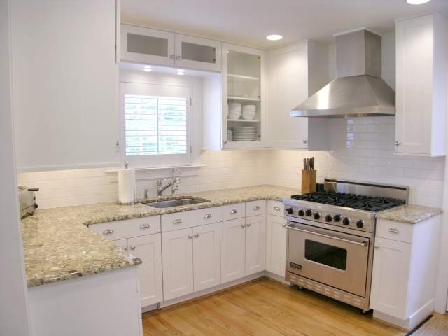 This is an example of a traditional u-shaped kitchen/diner in Dallas with a submerged sink, recessed-panel cabinets, white cabinets, concrete worktops, white splashback and stainless steel appliances.