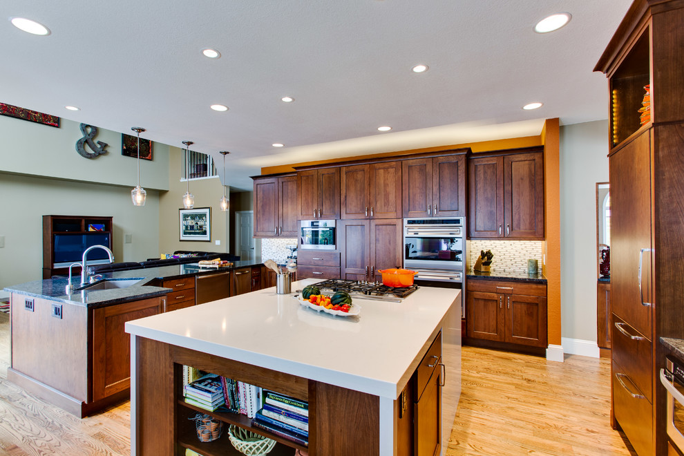 Example of a large transitional u-shaped medium tone wood floor eat-in kitchen design in Denver with a single-bowl sink, shaker cabinets, brown cabinets, quartz countertops, white backsplash, mosaic tile backsplash, colored appliances and an island
