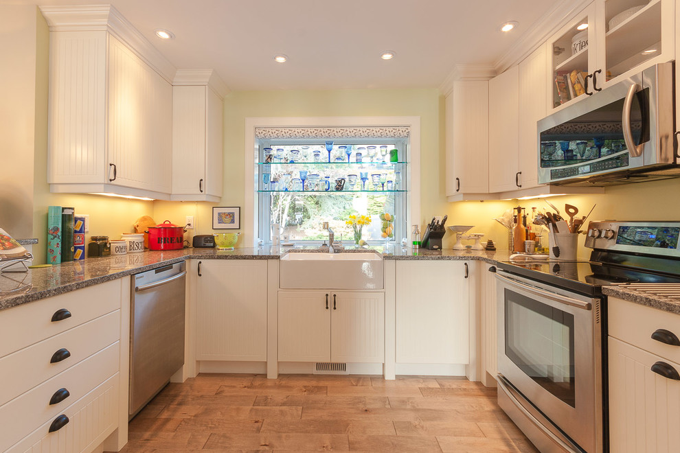 Klassische Küche in U-Form mit Landhausspüle, flächenbündigen Schrankfronten, beigen Schränken und Küchengeräten aus Edelstahl in Vancouver