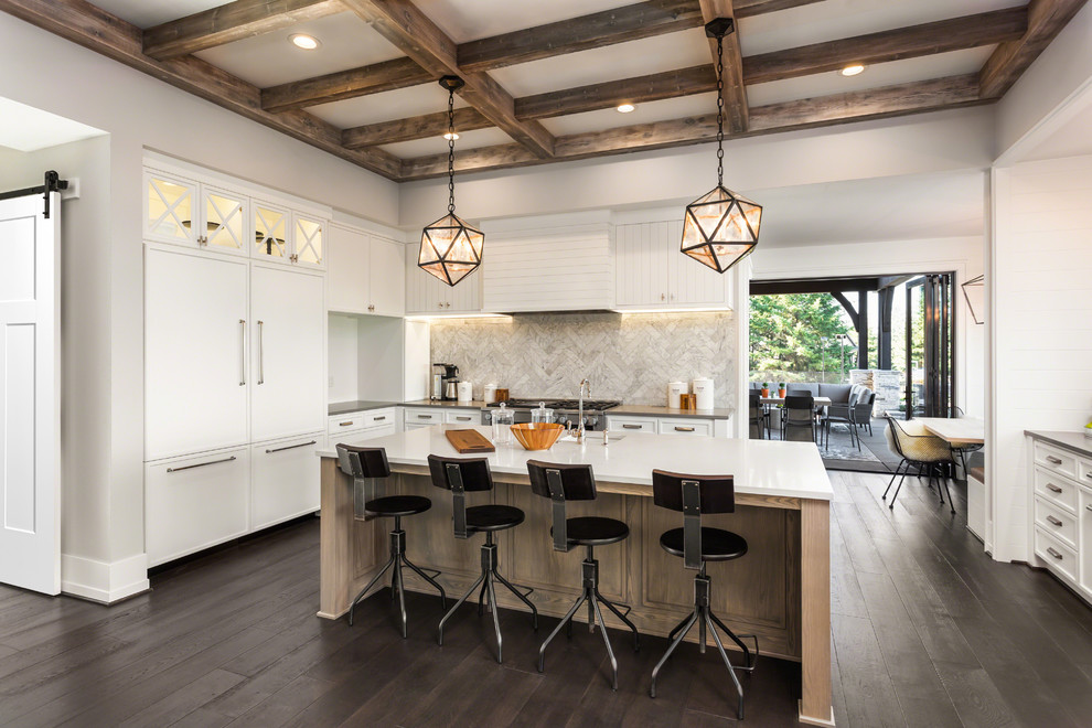 Photo of a large classic kitchen/diner in Los Angeles with a built-in sink, flat-panel cabinets, white cabinets, multi-coloured splashback, stainless steel appliances, dark hardwood flooring, an island, brown floors and white worktops.