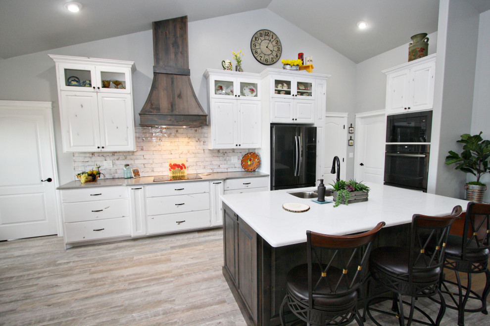 Exempel på ett mycket stort lantligt vit vitt kök, med en undermonterad diskho, släta luckor, vita skåp, bänkskiva i kvarts, vitt stänkskydd, stänkskydd i tegel, svarta vitvaror, cementgolv och en köksö
