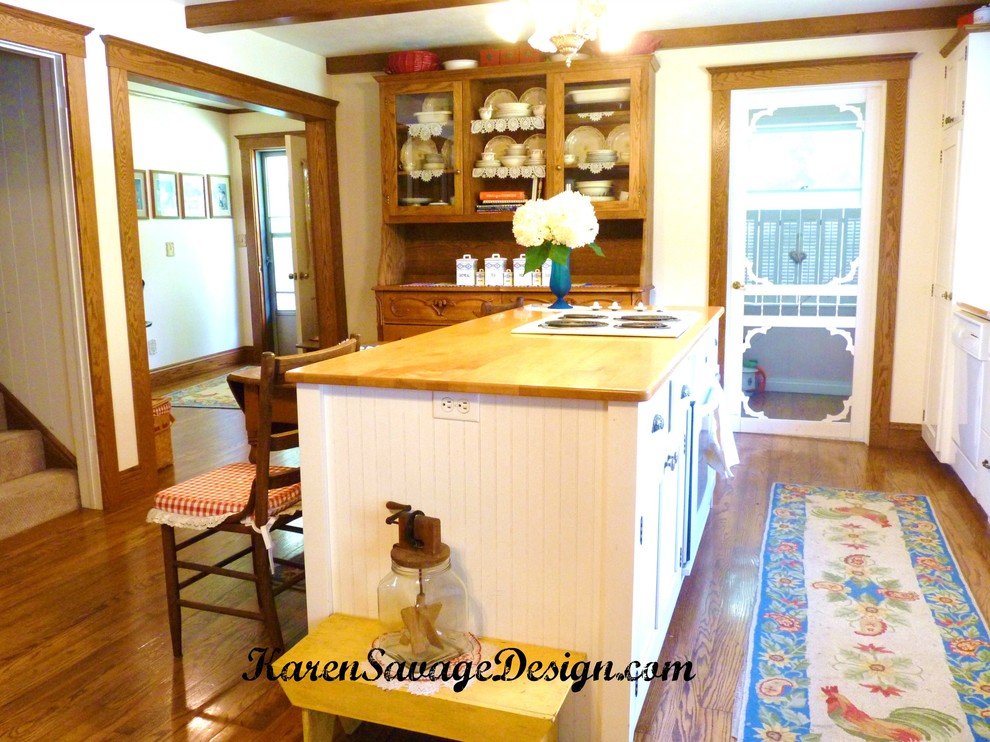 Foto på ett mellanstort lantligt kök, med en rustik diskho, släta luckor, vita skåp, träbänkskiva, vitt stänkskydd, vita vitvaror, mellanmörkt trägolv och en köksö