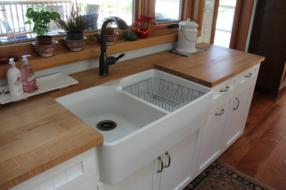 Inredning av ett lantligt mellanstort l-kök, med en rustik diskho, skåp i shakerstil, vita skåp, träbänkskiva, blått stänkskydd, glaspanel som stänkskydd, rostfria vitvaror och mellanmörkt trägolv