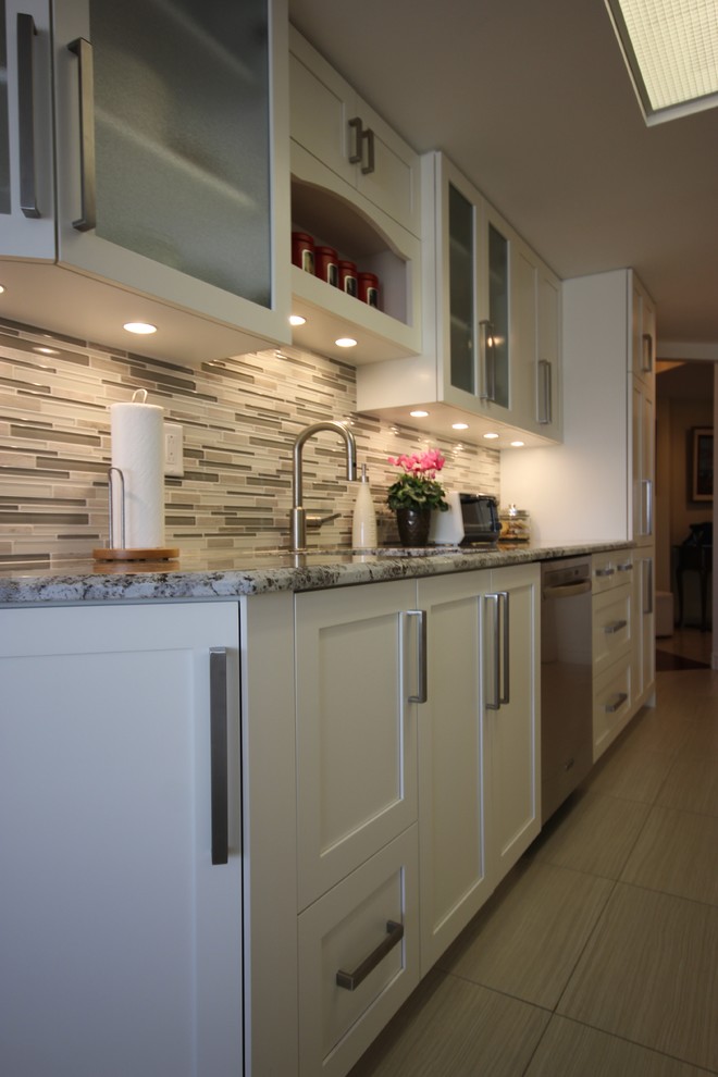 Modern inredning av ett mellanstort kök, med en undermonterad diskho, skåp i shakerstil, vita skåp, granitbänkskiva, grått stänkskydd, glaspanel som stänkskydd, rostfria vitvaror och klinkergolv i porslin