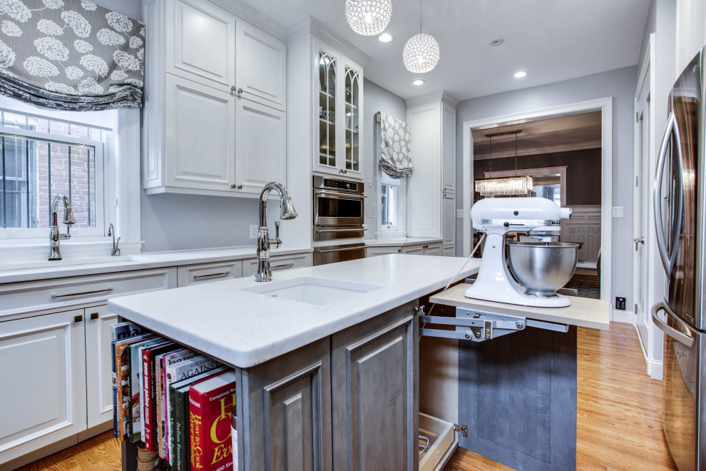 Medium sized traditional galley kitchen in DC Metro with a submerged sink, raised-panel cabinets, white cabinets, engineered stone countertops, stainless steel appliances, medium hardwood flooring, an island and white worktops.