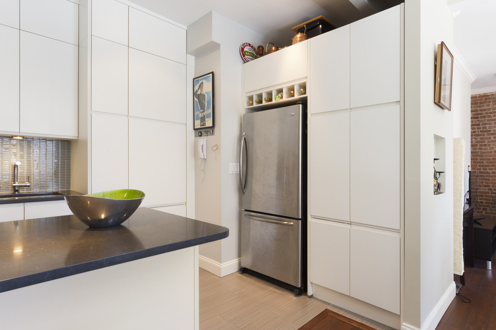 Foto på ett mellanstort funkis grå kök, med släta luckor, vita skåp, bänkskiva i kvarts, rostfria vitvaror, en undermonterad diskho, grått stänkskydd, stänkskydd i glaskakel, klinkergolv i porslin, en halv köksö och beiget golv
