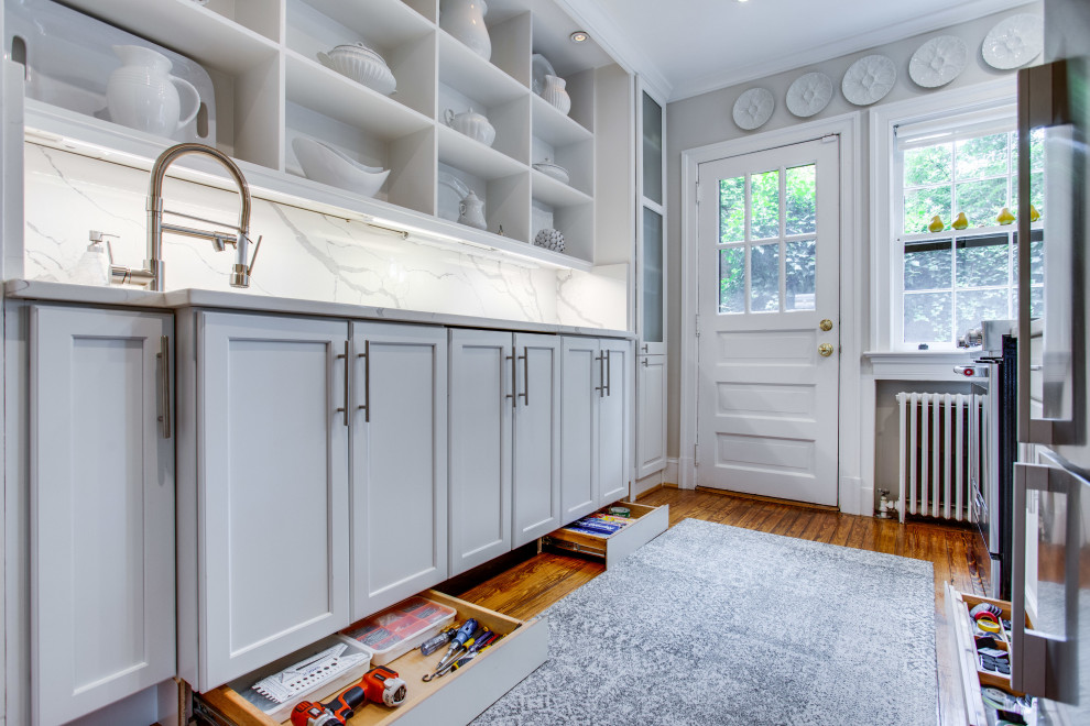 Small traditional galley enclosed kitchen in DC Metro with a submerged sink, recessed-panel cabinets, white cabinets, engineered stone countertops, engineered quartz splashback, stainless steel appliances, medium hardwood flooring and no island.