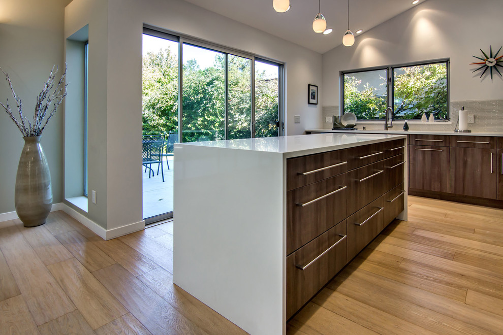 Example of a mid-century modern l-shaped eat-in kitchen design in San Francisco with an undermount sink, flat-panel cabinets, brown cabinets, quartz countertops, gray backsplash, glass tile backsplash and stainless steel appliances