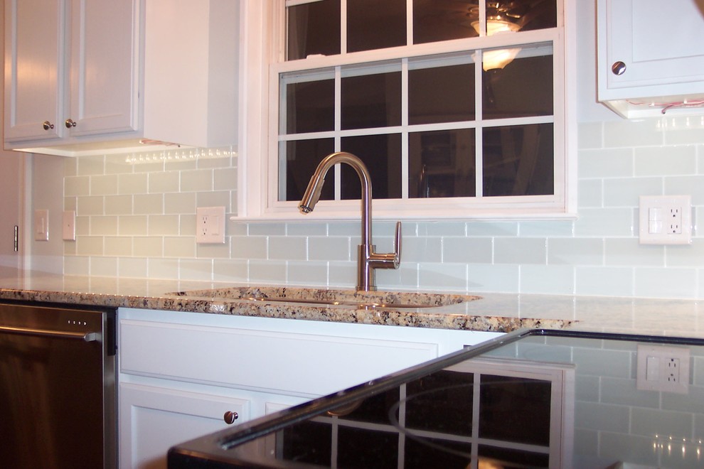 Klassische Wohnküche in L-Form mit Unterbauwaschbecken, weißen Schränken, Küchenrückwand in Weiß, Rückwand aus Glasfliesen und Küchengeräten aus Edelstahl in Sonstige