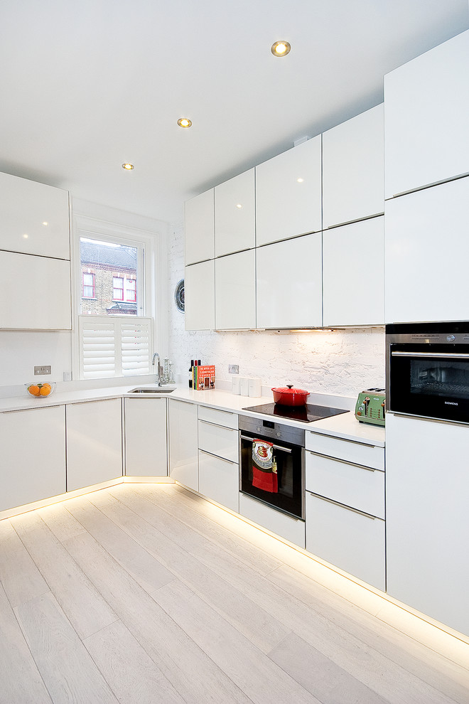 Kitchen - contemporary l-shaped light wood floor kitchen idea in London with flat-panel cabinets, white cabinets, white backsplash, no island and white countertops