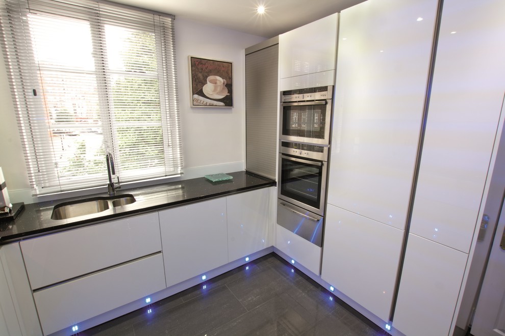 Idées déco pour une petite cuisine moderne en U avec des portes de placard blanches.