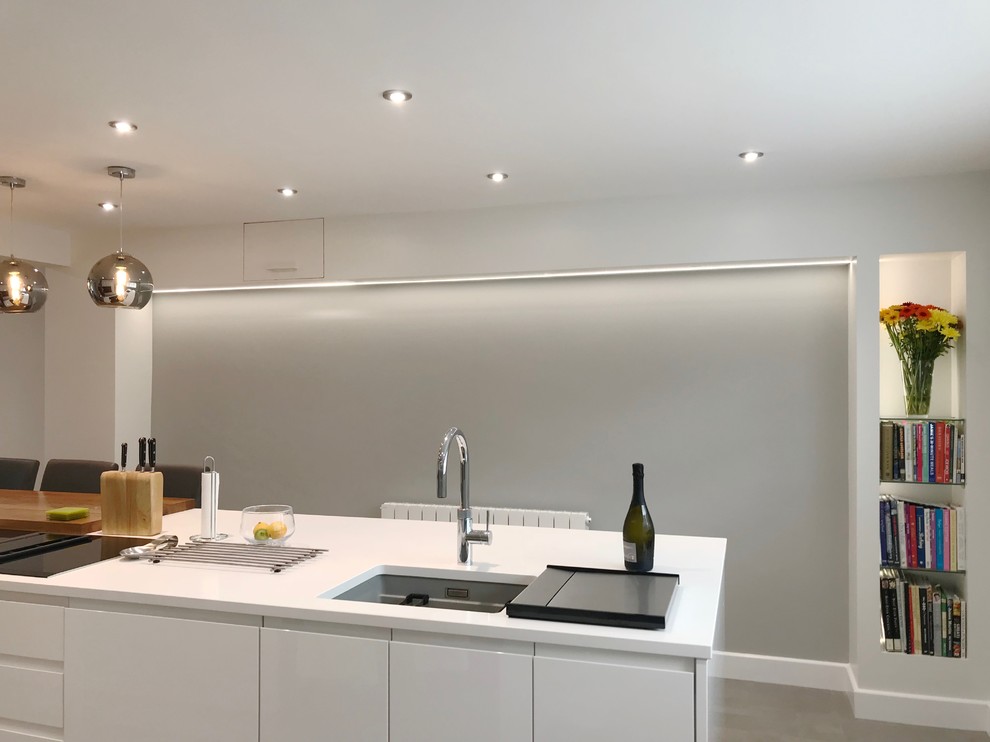 Photo of a large contemporary galley kitchen/diner in Buckinghamshire with flat-panel cabinets, white cabinets, quartz worktops, stainless steel appliances, porcelain flooring, an island, grey floors and white worktops.