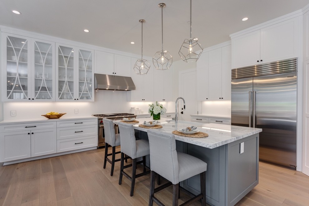 Eat-in kitchen - large transitional l-shaped light wood floor and multicolored floor eat-in kitchen idea in Los Angeles with an undermount sink, shaker cabinets, white cabinets, marble countertops, white backsplash, brick backsplash, stainless steel appliances and an island