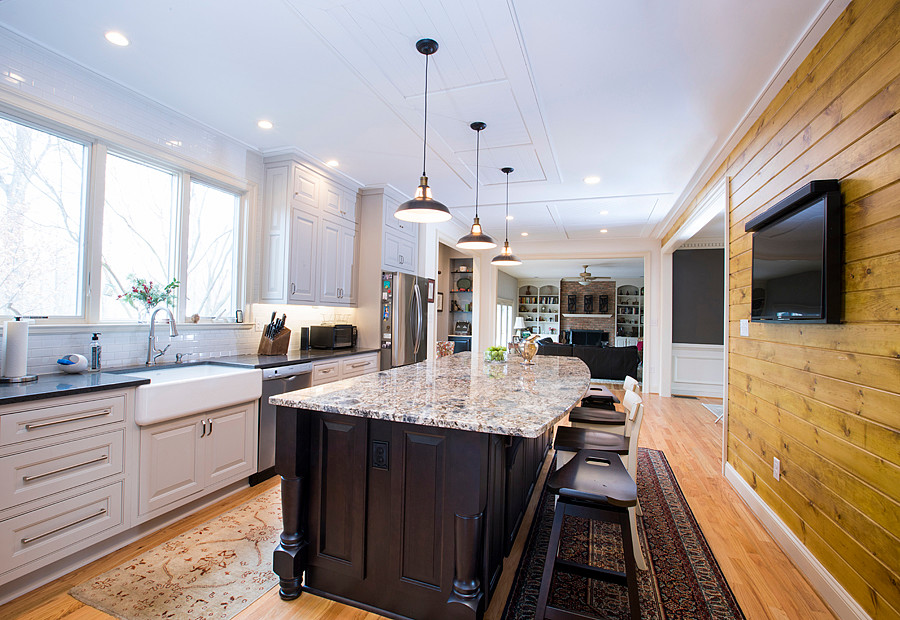 Inredning av ett klassiskt mellanstort flerfärgad flerfärgat kök, med en rustik diskho, luckor med upphöjd panel, vita skåp, granitbänkskiva, vitt stänkskydd, stänkskydd i tunnelbanekakel, rostfria vitvaror, mellanmörkt trägolv, en köksö och brunt golv