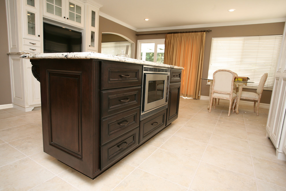 Eat-in kitchen - large traditional l-shaped porcelain tile eat-in kitchen idea in Orange County with an undermount sink, recessed-panel cabinets, white cabinets, granite countertops, beige backsplash, porcelain backsplash, stainless steel appliances and an island