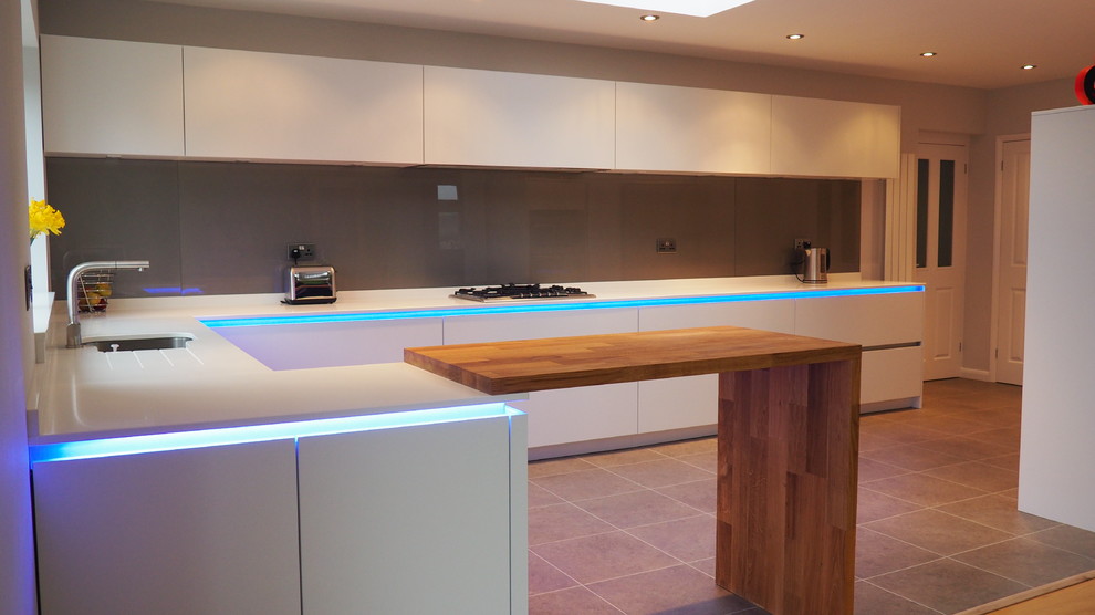 Large contemporary l-shaped kitchen/diner in Other with a double-bowl sink, flat-panel cabinets, white cabinets, quartz worktops, grey splashback, glass sheet splashback, stainless steel appliances, porcelain flooring and beige floors.