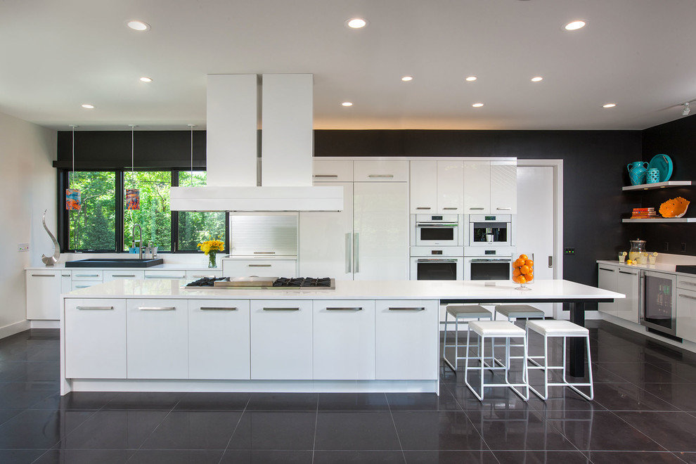 Bild på ett mycket stort funkis kök, med en nedsänkt diskho, släta luckor, vita skåp, bänkskiva i kvarts, vitt stänkskydd, rostfria vitvaror, marmorgolv och en köksö