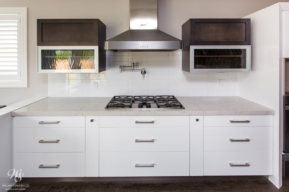 Modern inredning av ett stort kök, med en undermonterad diskho, släta luckor, vita skåp, bänkskiva i kvarts, vitt stänkskydd, stänkskydd i keramik, färgglada vitvaror, mellanmörkt trägolv och en köksö