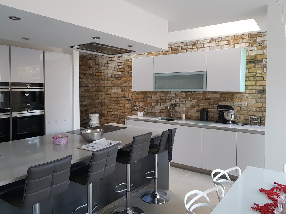 Esempio di una cucina design di medie dimensioni con lavello da incasso, ante lisce, ante bianche, top in quarzite, paraspruzzi in mattoni e elettrodomestici neri