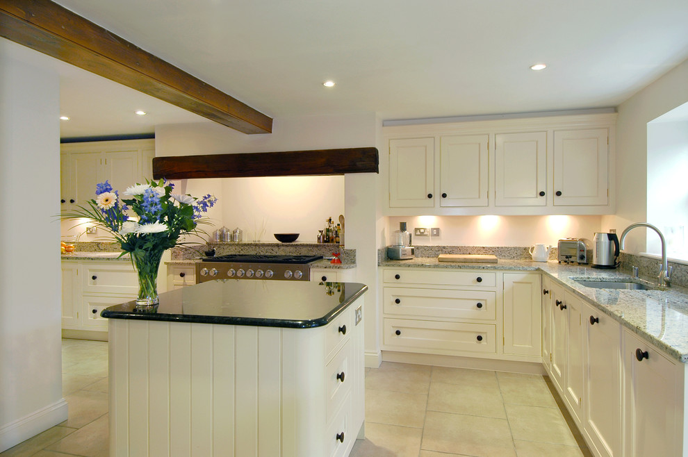 Foto på ett mellanstort vintage kök, med en undermonterad diskho, rostfria vitvaror, luckor med infälld panel, granitbänkskiva, klinkergolv i keramik, en köksö och vita skåp
