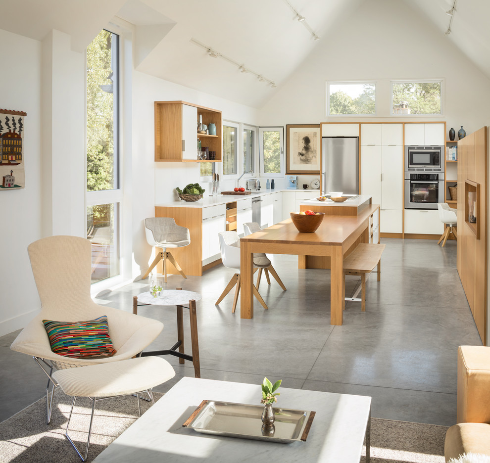 This is an example of a contemporary u-shaped open plan kitchen in Boston with a submerged sink, flat-panel cabinets, white cabinets, white splashback, stainless steel appliances, concrete flooring, an island, grey floors and white worktops.