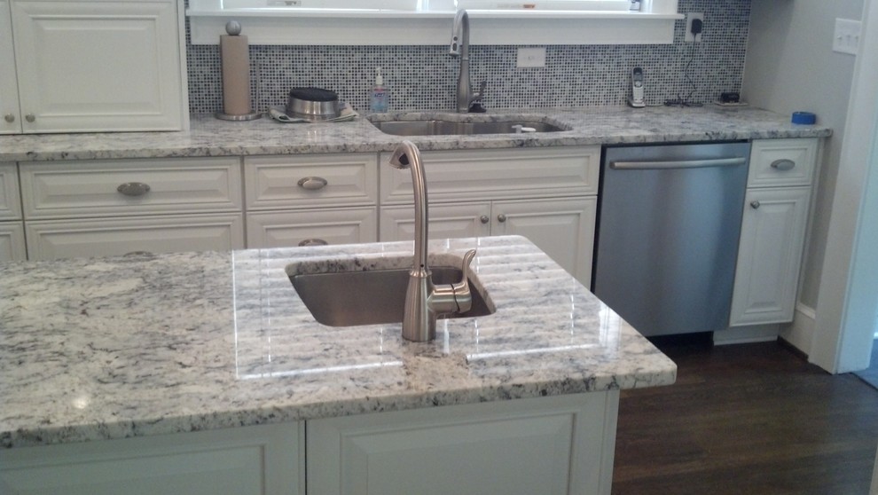This is an example of a medium sized contemporary grey and cream l-shaped kitchen/diner in Atlanta with a submerged sink, raised-panel cabinets, white cabinets, granite worktops, grey splashback, mosaic tiled splashback, stainless steel appliances, dark hardwood flooring, an island and brown floors.